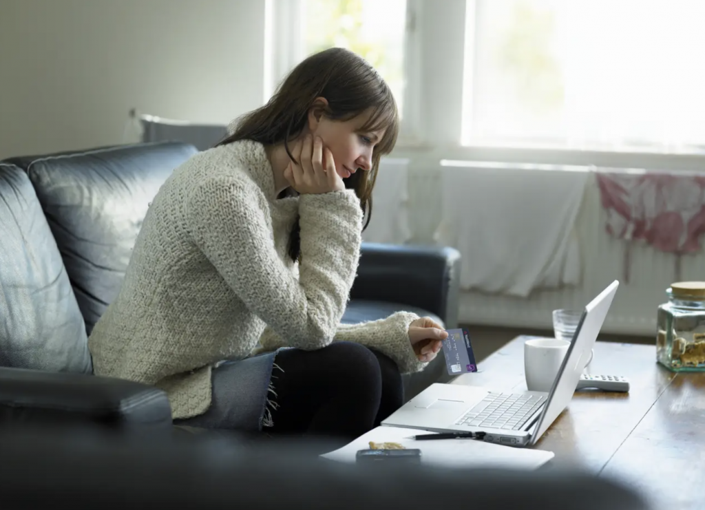 photo of seated woman using credit card to pay online