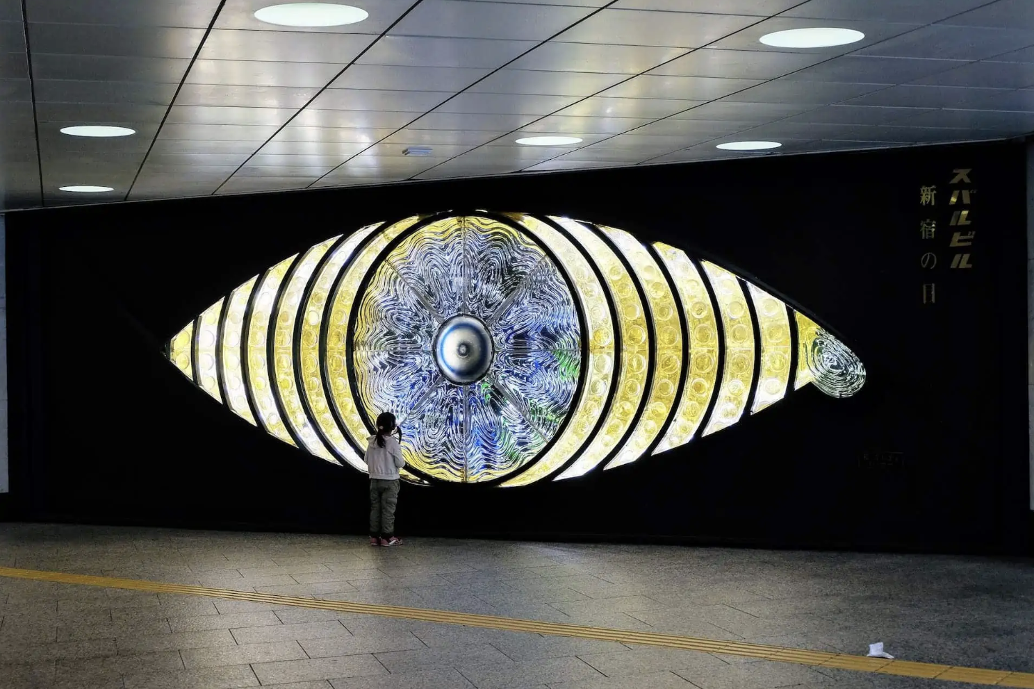 photo of person standing in front of a large eye artpiece
