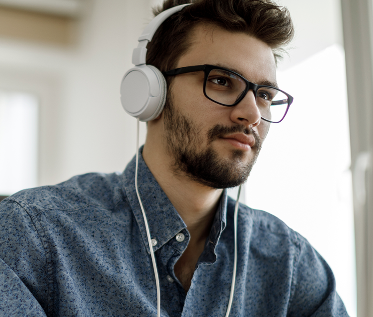 photo of man listening to headphones while working at computer