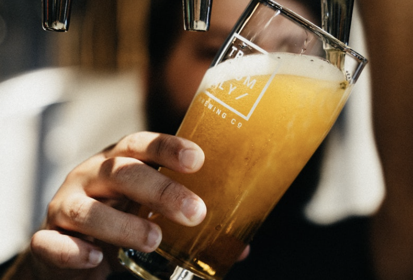 photo of person filling a glass with draft beer