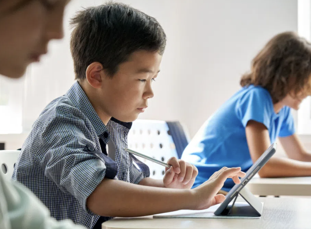 photo of children at desks working on laptop computers