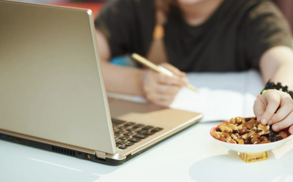 photo of person eating while working on laptop