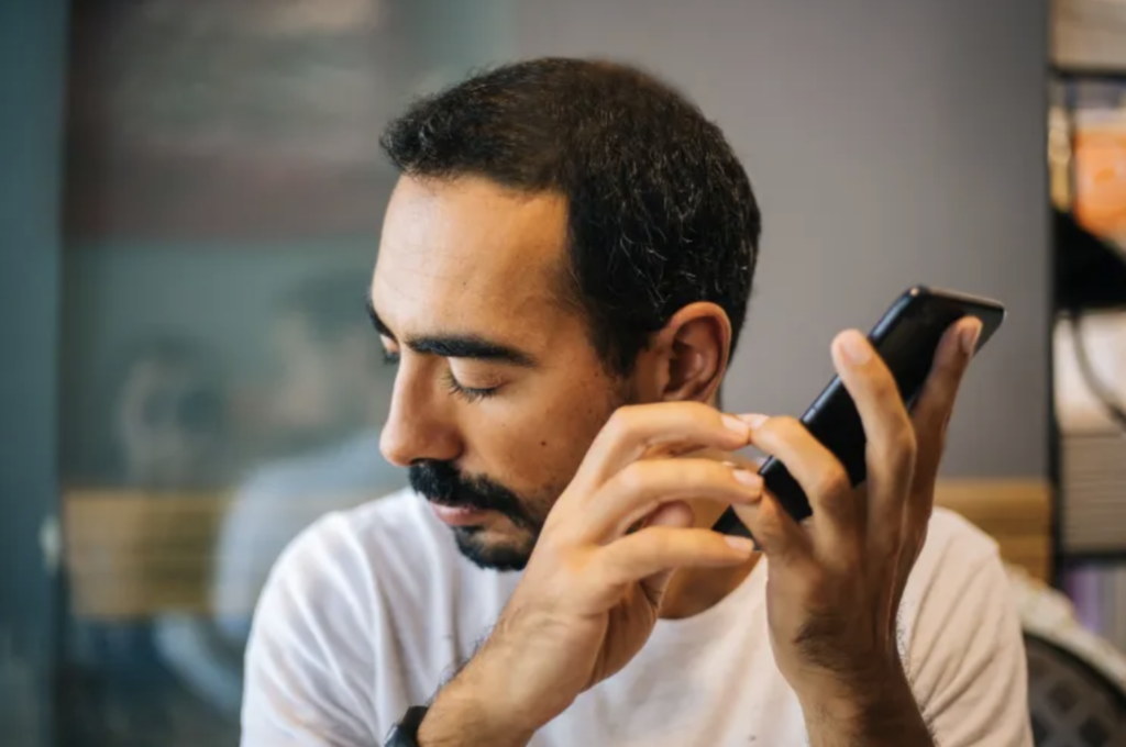 Image of man with closed eyes listening to smartphone he's holding